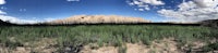 a panoramic view of a grassy field with mountains in the background